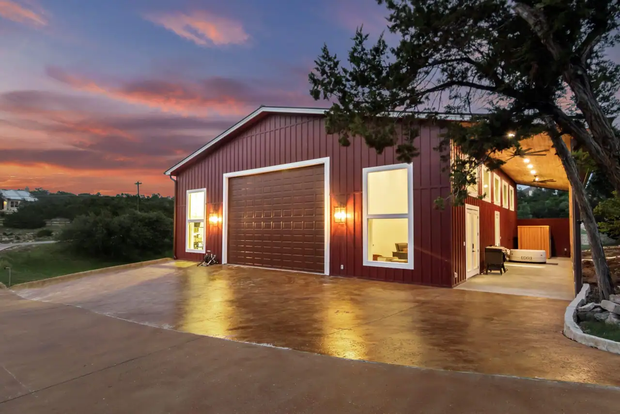 Finished Ridge Rock barn and shop lit at dusk on a Hill Country property